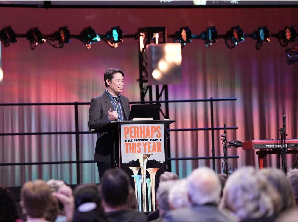 Pastor Steve Cioccolanti teaching at the Bible Prophecy Summit on stage with colorful lighting