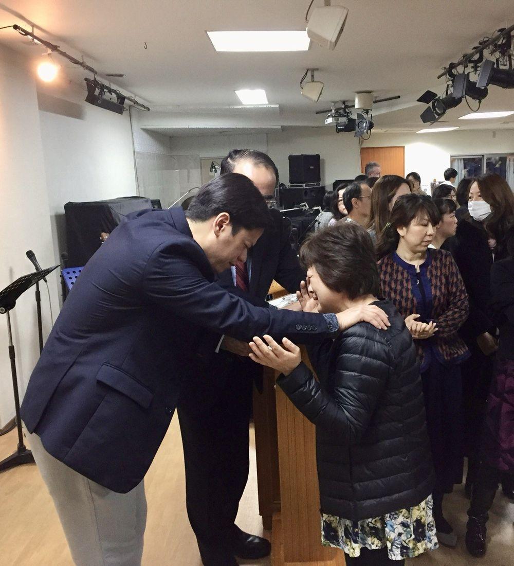 Pastor Steve Cioccolanti praying for a woman at Shinjuku Church ministry in Japan with a line of people waiting