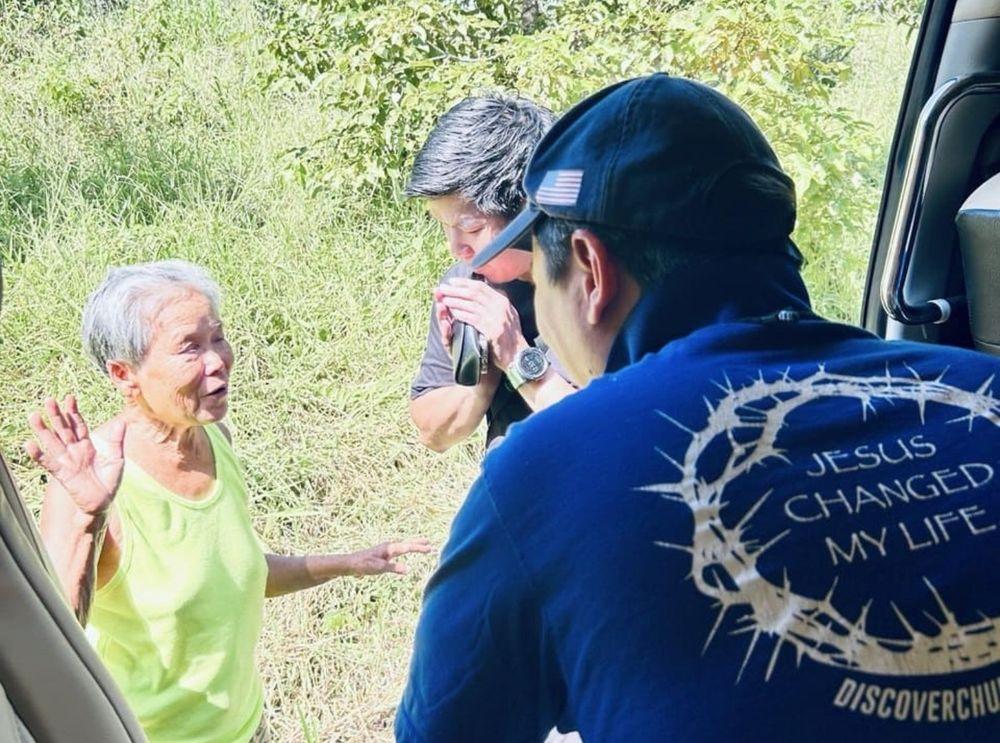 Pastor Steve Cioccolanti praying with a woman during Thailand ministry outreach, wearing a Jesus Changed My Life Discover Church shirt